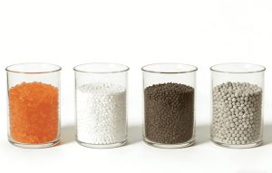 Four desiccant materials displayed in glass beakers for comparison