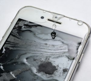 Wet smartphone with water droplets for silica gel drying safety guide